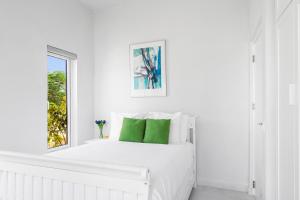 een witte slaapkamer met een wit bed met groene kussens bij San Fuego 28-W in Santa Cruz