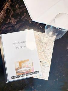 een boek en een glas wijn op een tafel bij Nobel-Prize-Appartement in Graz