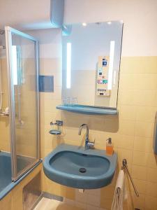 een badkamer met een blauwe wastafel en een douche bij Nobel-Prize-Appartement in Graz