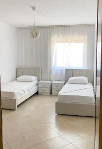 Cette chambre blanche dispose de 2 lits et d'une fenêtre. dans l'établissement Aldo Apartment, à Tirana