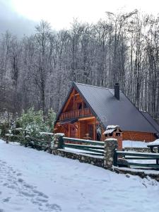 a log cabin in the snow with a fence at Cozy Cabin in the Woods in Brezovica
