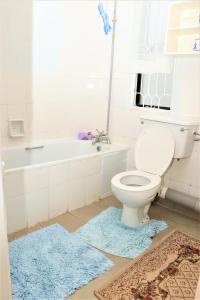 a bathroom with a toilet and a tub and a rug at Furaha Maisonette Fully Furnished apartment Nyayo Estate Nairobi Kenya Namba Simu sufuri saba sufuri moja moja nne tisa sufuri sufuri saba next to JKIA Jomo kenyatta International Airport,Next to SGR Nairobi Terminus Next To Kenya Airways Pride Centr in Nairobi