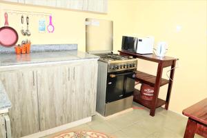 a kitchen with a stove and a microwave at Furaha Maisonette Fully Furnished apartment Nyayo Estate Nairobi Kenya Namba Simu sufuri saba sufuri moja moja nne tisa sufuri sufuri saba next to JKIA Jomo kenyatta International Airport,Next to SGR Nairobi Terminus Next To Kenya Airways Pride Centr in Nairobi