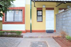 a yellow and white house with a white door at Furaha Maisonette Fully Furnished apartment Nyayo Estate Nairobi Kenya Namba Simu sufuri saba sufuri moja moja nne tisa sufuri sufuri saba next to JKIA Jomo kenyatta International Airport,Next to SGR Nairobi Terminus Next To Kenya Airways Pride Centr in Nairobi