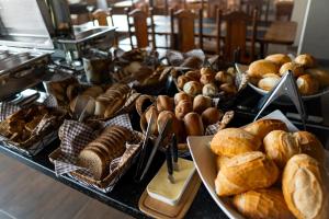 a table filled with lots of different types of bread at Hotel Nixon Próximo, Rodoviária, Prefeitura e a Matriz central in Itaí