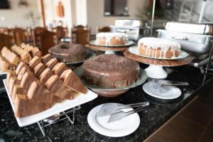a counter topped with cakes and other desserts on plates at Hotel Nixon Próximo, Rodoviária, Prefeitura e a Matriz central in Itaí