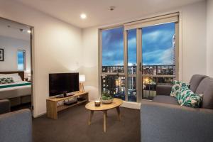 sala de estar con sofá, TV y cama en Barclay Suites en Auckland