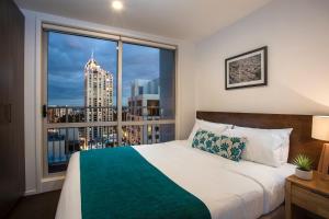 sypialnia z łóżkiem i dużym oknem w obiekcie Barclay Suites w Auckland