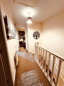 a hallway with a staircase with a clock on the wall at 5 STAR LUXURY BIG HOUSE, JACUZZI SPA HOT TUB, PARKING, LIVERPOOL CITY CENTRE, SLEEPS 10, EASY LOCK BoX ENTRY! NO PARTIES! in Liverpool