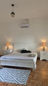 um quarto com uma cama branca e duas mesas de cabeceira em Casa Paz em Parrita