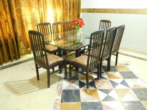 a dining room with a glass table and chairs at Moon Palace Hotel Lahore in Lahore