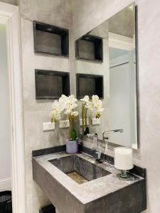 een badkamer met een wastafel met een spiegel en bloemen bij Stone residence in Caïro