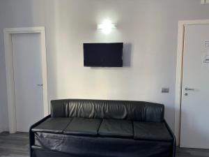 羅馬的住宿－The Manzoni，墙上有电视的房间里一张黑色皮沙发