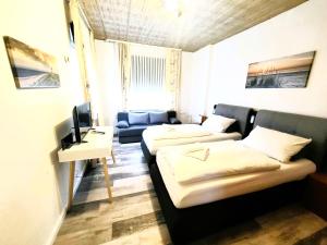 ein Wohnzimmer mit 2 Betten und einem Sofa in der Unterkunft City Center Hotel Garni Cuxhaven in Cuxhaven