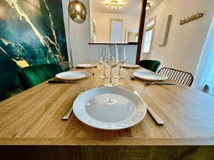 een houten tafel met een witte plaat en wijnglazen bij GREENWOOD CHATOU - 1 chambre - 4 Pers - Wifi in Chatou