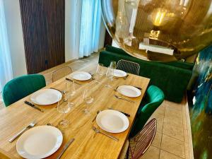 een houten tafel met borden en wijnglazen erop bij GREENWOOD CHATOU - 1 chambre - 4 Pers - Wifi in Chatou