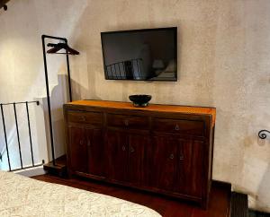 a tv on a wall with a wooden dresser at Boutique Villa in Antigua in Antigua Guatemala