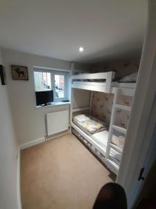 a small room with two bunk beds and a window at Daisy Cottage in Warminster