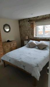 a bedroom with a large bed and a brick wall at Daisy Cottage in Warminster