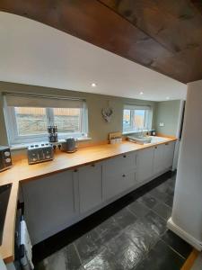 a kitchen with white cabinets and a wooden counter top at Daisy Cottage in Warminster