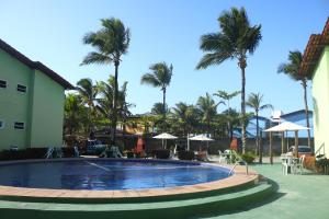 uma piscina num resort com palmeiras em Apto a 300m da praia AxéMoi em Porto Seguro