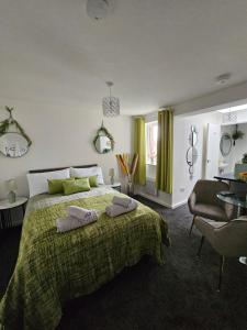 a bedroom with a large bed with a green blanket at Luxury Studio Stevenage in Stevenage