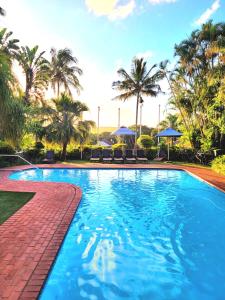una piscina con palme e ombrelloni di Perna Perna Lodge St Lucia a St Lucia