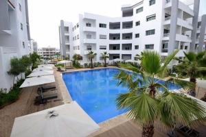 a swimming pool in front of a building with umbrellas at La Siesta Beach Resort in Mohammedia