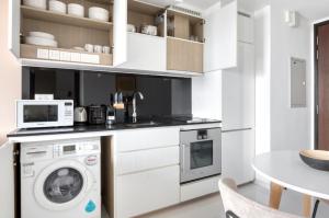 cocina con lavadora y microondas en The Dapper Digs 2BR Apartment in Singapore en Singapur