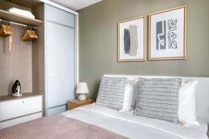 una camera da letto con un grande letto bianco e due quadri appesi al muro di The Dapper Digs 2BR Apartment in Singapore a Singapore