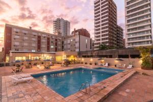 a large swimming pool in a city with tall buildings at Farol Hotel in Torres