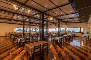 a large room with tables and chairs and windows at Farol Hotel in Torres