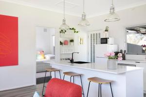 a kitchen with a white counter and stools at The Alfred, Mittagong in Mittagong