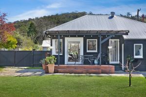 a small blue house with a porch with a bench at The Alfred, Mittagong in Mittagong