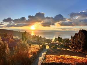 a sunset over a town with the ocean in the background at Dawn House - Lago Titicaca in Ocosuyo