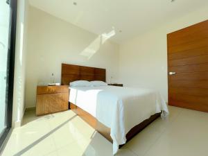 - une chambre avec un lit blanc et des placards en bois dans l'établissement Departamento en CDMX, zona norte, à Mexico