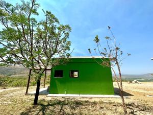 ein grünes Haus mitten auf einem Feld in der Unterkunft Canastra - Chalés Canário de Minas in São João Batista do Glória