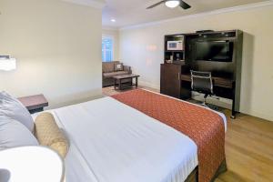a hotel room with a bed and a flat screen tv at Clarion Collection Wilkie's Inn Pacific Grove - Monterey in Pacific Grove