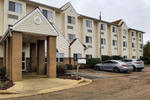 a large building with cars parked in a parking lot at Starkville Inn & Suites in Starkville
