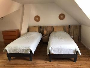 two beds in a attic bedroom with white sheets at Le saint Pierre in Roye