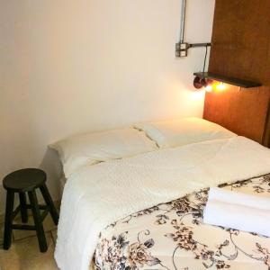 two twin beds in a room with a stool at Micasa Hostel - Congonhas in Sao Paulo