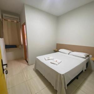 1 dormitorio con 1 cama blanca y 2 toallas en Hotel Pousada Aeroporto, en Ponta Porã