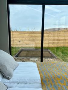 a bedroom with a bed and a large window at Glass roof lodge with private hot tub in Reykholt