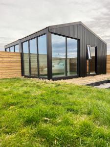 una casa negra con ventanas de cristal en un campo de césped en Glass roof lodge with private hot tub, en Reykholt