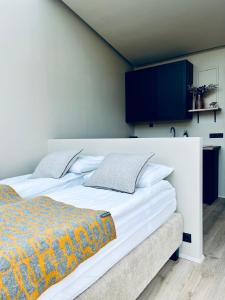 una camera da letto con un grande letto bianco e una TV a parete di Glass roof lodge with private hot tub a Reykholt