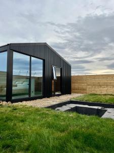 ein schwarzes Haus mit einer großen Glastür in der Unterkunft Glass roof lodge with private hot tub in Reykholt