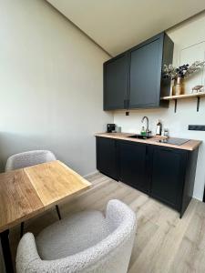 uma cozinha com armários pretos e uma mesa e cadeiras de madeira em Glass roof lodge with private hot tub em Reykholt