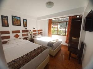 a hotel room with two beds and a window at PAQARIQ INN HOTEL in Machu Picchu