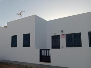 een wit gebouw met zwarte deuren en ramen bij Casa Carmen Dolores in Caleta de Sebo