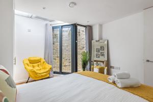 a bedroom with a large bed and a yellow chair at Trafalgar Square Arty Apartment in London
